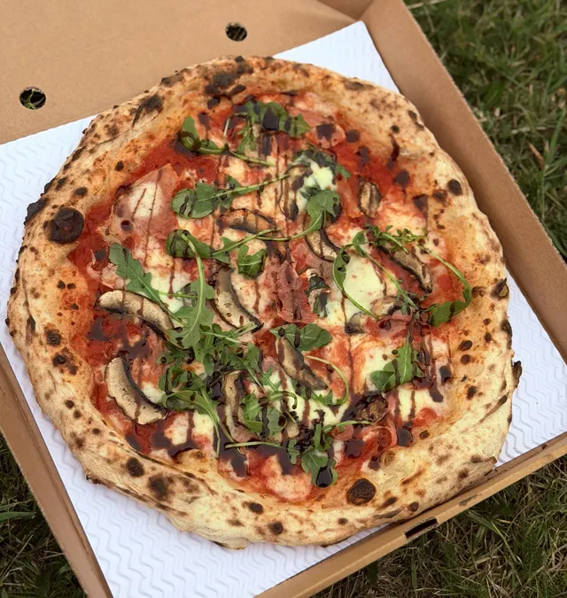 A pizza topped with mushrooms, rocket and balsamic glaze